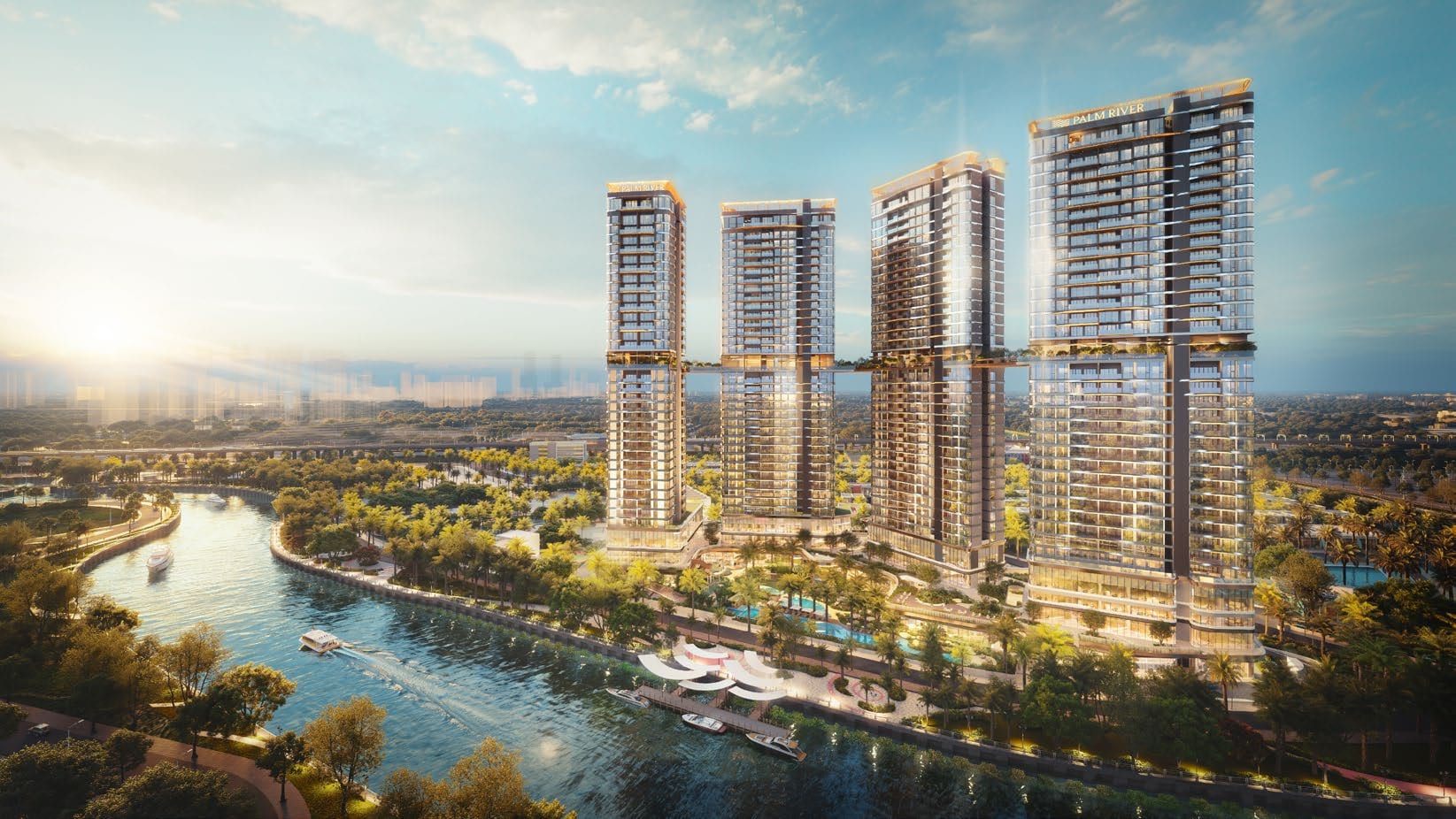 The same site from the water: four towers set back behind the riverside park, with the central district on the horizon.